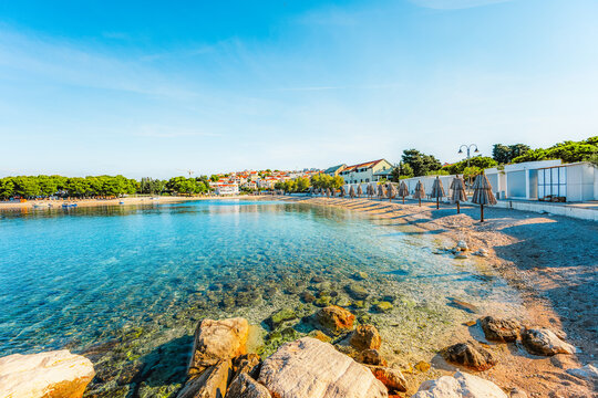 Scenic coastal promenade and the old stone town of Primosten under a clear blue sky, Dalmatia, Croatia.
