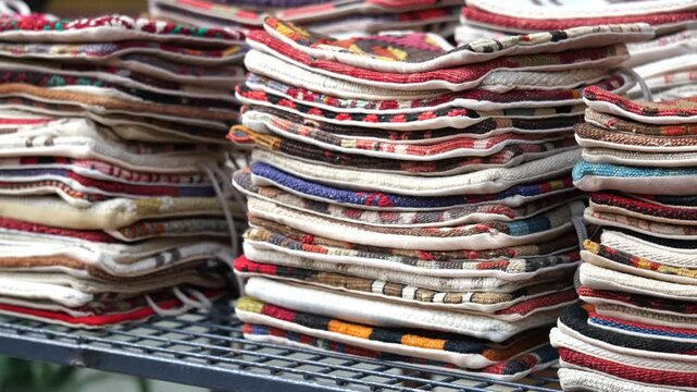 Close up video footage showing many colorful handmade fabric stacks for sale on display.