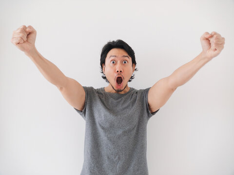 Happy and surprise reaction of Asian man in grey t-shirt isolated on white.