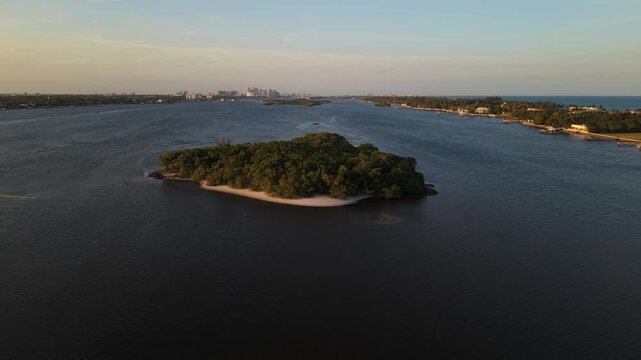Circling golden hour drone shot circling Hunters Island near Summa Beach Park on the ICW, Intracoastal Waterway near S. Flagler Dr. in W. Palm Beach Florida and the Atlantic Ocean in the background.
