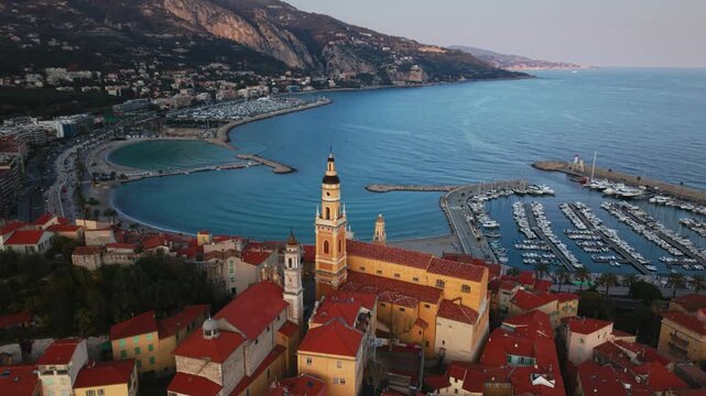 Basilique Saint-Michel, Menton old town red rooftops toward calm Mediterranean Sea at sunset, France