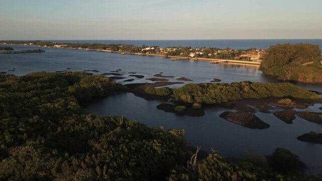 Drone flying during golden hour northeast over the ICW, Intracoastal Waterway in Florida near Summa Beach and S. Flagler Drive showing many islands, waterfront homes and the Atlantic Ocean distant.