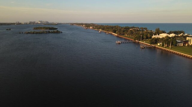 Drone flying north at golden hour toward Hunters Island in the ICW Intracoastal Waterway near Summa Beach Park and S. Flagler Dr. with the barrier island and Atlantic Ocean in view along S. Ocean Blvd