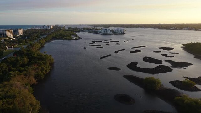 drone flying in golden hour near Summa Beach Park south above the Intracoastal Waterway in Palm Beach County Florida toward Ibis Island with South Ocean Blvd. and high-rise buildings in the distance.