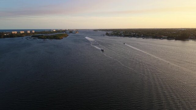 Drone evening golden hour shot flying south over the ICW Intracoastal Waterway near Summa Beach Park in West Palm Beach Florida with boats motoring on the water