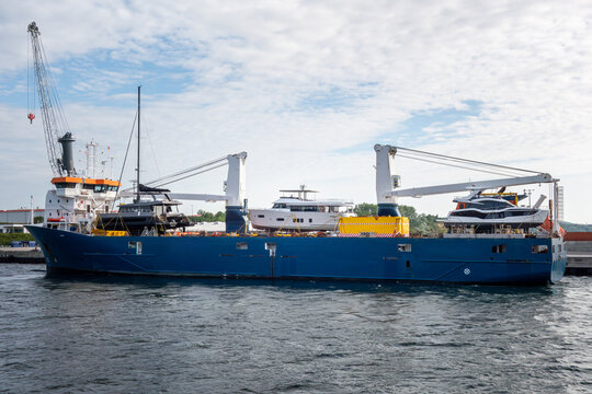 Heavy lift cargo ship transporting luxury yachts at port, maritime logistics vessel with onboard cranes handling oversized cargo, global shipping, marine transport