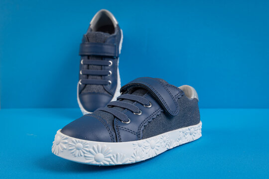 Stylish kids' sneakers with velcro straps on blue background. Children's fashion footwear for active play and back to school concept.