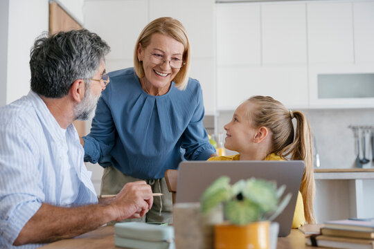 Grandparent and girl learning together at home using laptop