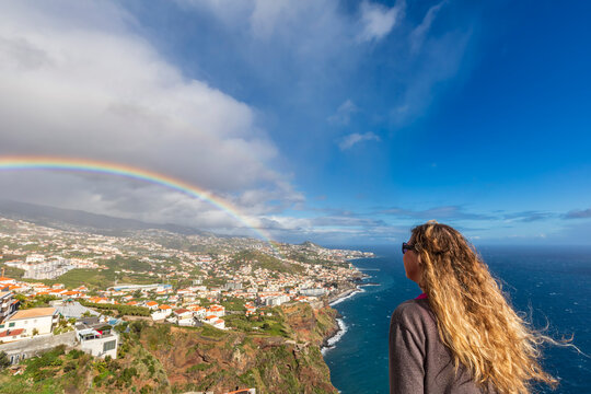 Tourist at Miradouro do Rancho overlooks rainbow and C�mara de Lobos
