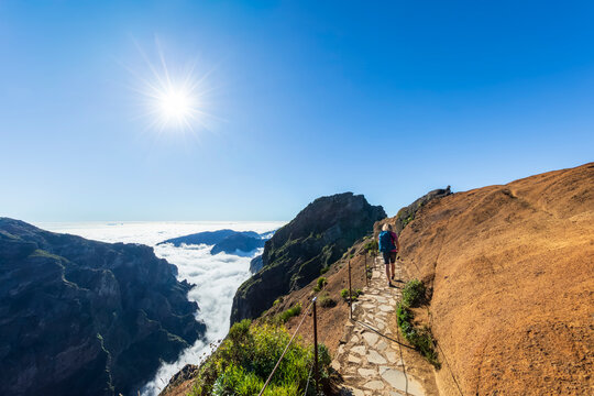 Tourist hiking on PR1 trail at Pico do Arieiro in Madeira with sunny sky