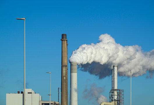 Coal fired powerplant with smoke emissions and lampposts in spring