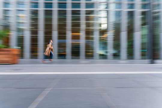 Businesswoman running in city with motion blur outside modern building