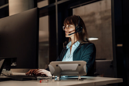 Professional with headset working overtime in modern office at night