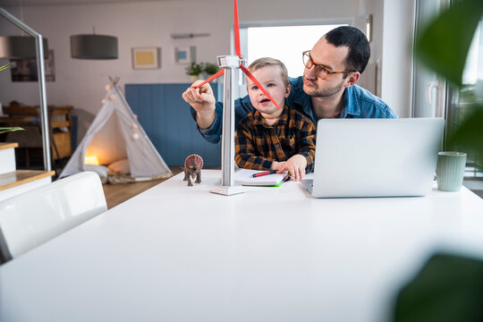 Father and son learning with wind turbine model at home office