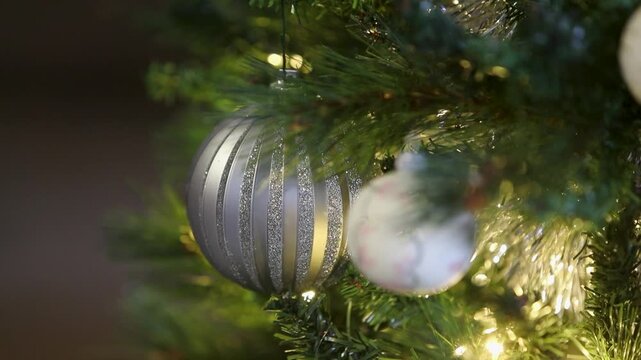 Un sapin de No&euml;l illumin&eacute;, d&eacute;cor&eacute; pour les f&ecirc;tes de fin d'ann&eacute;e. Gros plan sur des d&eacute;coration d'un sapin de no&euml;l artificiel, avec guirlande lumineuse en fond. 