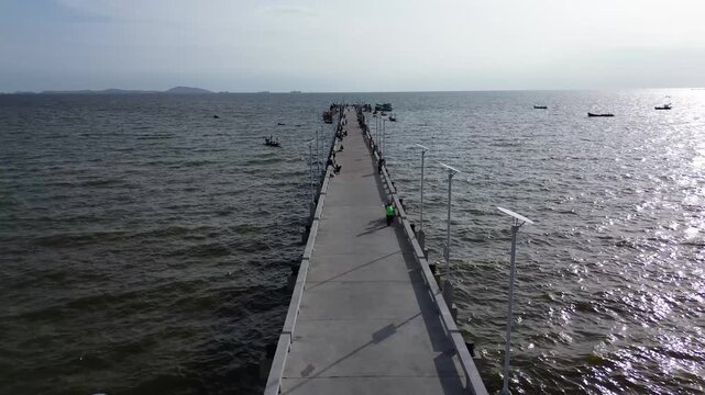 Aerial view of a bridge, boats, dark sea water, and fishermen at Bang Saen, Chonburi, Thailand
