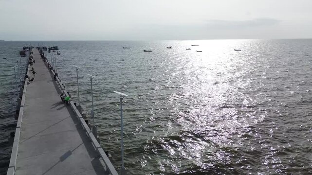 Aerial view of fishing boats, a bridge, and reflections on the sea at Bang Saen, Thailand
