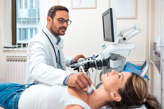 Male doctor performing thyroid ultrasound examination on female patient in clinic. Healthcare and medicine concept. Professional physician using sonogram equipment. Medical diagnostic in hospital.
