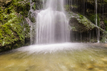 Fototapeta premium Scenic waterfall in Bavarian Alps forest with cascading water and mossy rocks close up long exposure