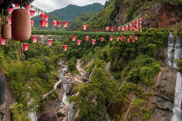 Waterfalls and decorated briges leading to the mountain village along rocky cliffs in Wangxian Valley, Shangrao, Jiangxi, China