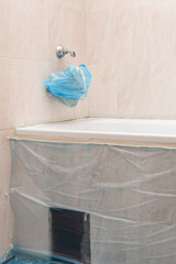 Bathtube covered with protective tape to prevent damage during the remodeling, Bathtub prepared for reglazing, faucet wrapped and area covered with plastic film.
