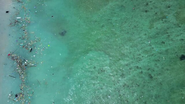 Ocean water showing a sea turtle swimming near the shore and accumulating plastic waste, highlighting environmental pollution impact. Magic aerial view overflight flyover panorama drone