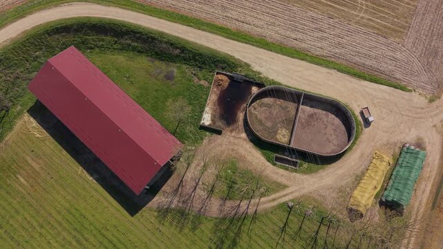 Aerial view of an open manure lagoon and barn on an Italian farm, showing storage and processing of liquid fertilizer before field application.