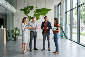 Fototapeta premium Business people talking in modern office lobby with world map.