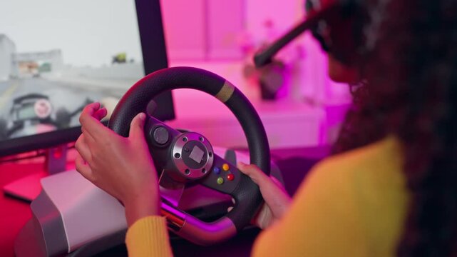 African American teenage girl playing online racing video game on computer. 