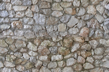 Fototapeta premium Rough stone wall with irregular shapes and natural texture outdoor