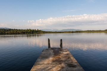 Obraz premium Wooden jetty at Kirchsee lake with a scenic view of the Bavarian Alps in summer 