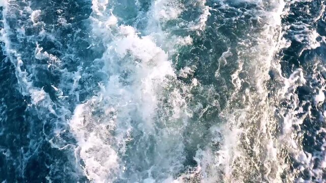 Close-up of turbulent ocean water with foam and bubbles in constant motion. Dynamic natural texture conveying power, freshness and energy of the sea.
