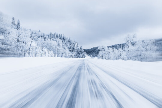 Distant rear view of a car driving along an ice covered forest highway with the illusion of movement, Steamboat Springs, Colorado, USA
