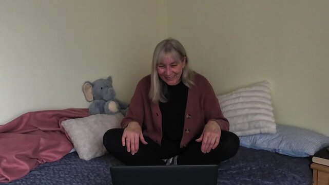 Mature woman video chatting on laptop with different emotions at home