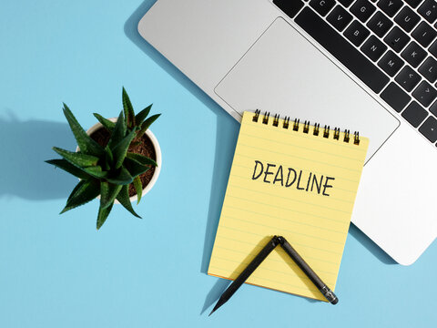 Deadline is approaching: laptop, notepad and pencil on blue background
