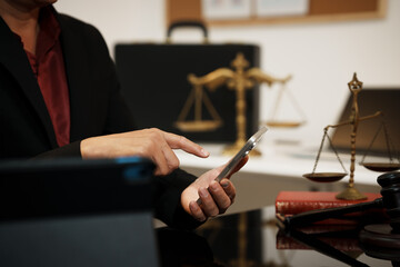 Businessman in office using smartphone beside gavel and scales of justice, legal consultation and...