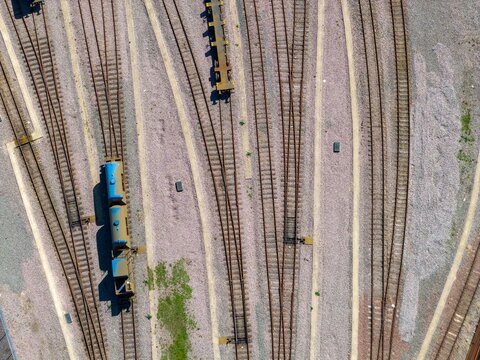 Top down aerial of rail yard in York in the UK with stacked sleepers multiple tracks and freight wagons arranged across an industrial landscape in early spring with strong linear patterns