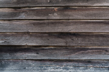 Obraz premium Texture of old weathered dark wooden wall planks arranged horizontally held together with nails. Rustic background features wood grain and aged surface details for retro vintage design.