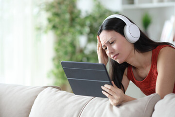 Sad asian woman checking online content on tablet