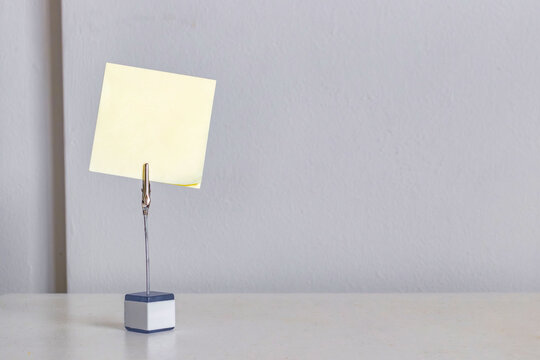 Empty yellow sticky note clipped on stand over light background, minimal office concept with copy space for text or reminder