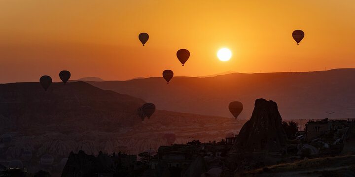 Hot air balloons float over the mountains of Cappadocia at sunrise.