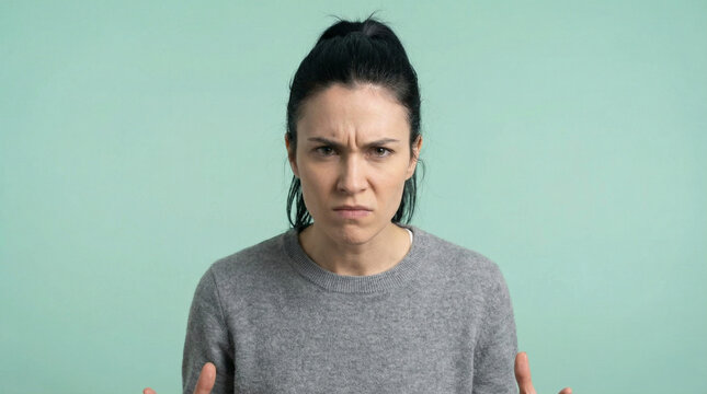 Portrait of an Angry Young Woman Looking at the Camera with a Furious and Frustrated Expression Against a Plain Background