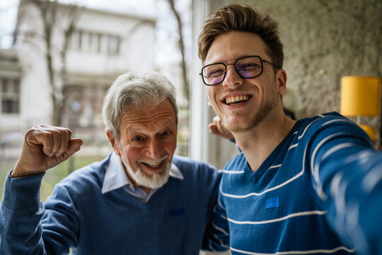 Grandfather and grandson celebrating success together taking selfie