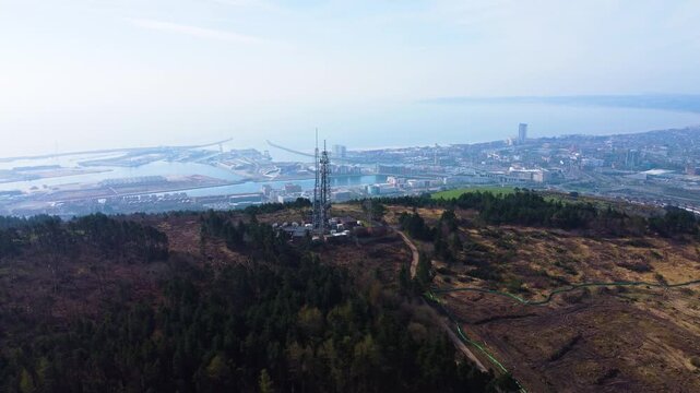 Aerial High Above TV Radio Transmitter Beaming Down to City Below with Hazy Atmosphere. Drone Clip Filmed in Swansea, UK.