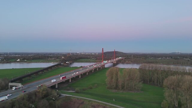 Drone flying parallel to bridge showing sunrise traffic and calm atmosphere