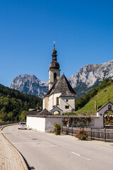 Fototapeta premium Scenic view of St Sebastian church in Ramsau with Ramsauer Ache river and Bavarian Alps 