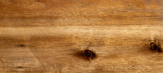 Natural light brown wooden board surface with organic grain patterns and dark knots showing...