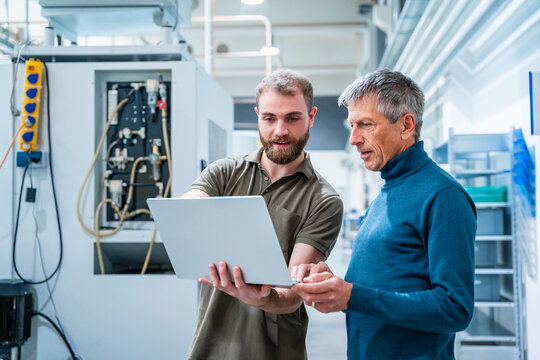 Two men discussing business in a production hall using a tablet