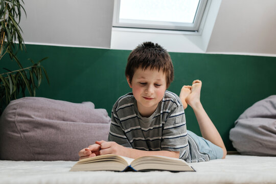 Child reading a book indoors lying on floor in a cozy home environment