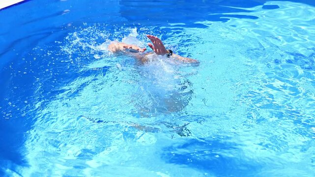 Man drowning in blue swimming pool calling for help. Water safety, accidental drowning and rescue concept. Person in distress submerged under water splashing and reaching out hand. Danger and accident